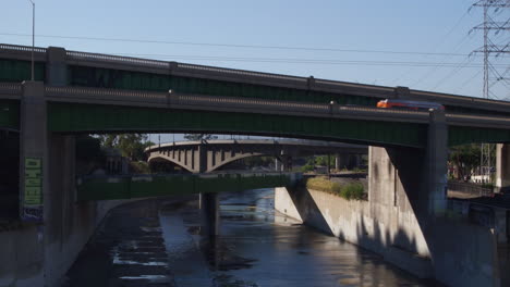 drone shot of los angeles traffic going on a bridge above the iconic la river