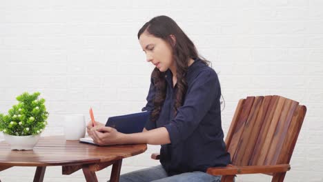 indian girl writing a book at a cafe