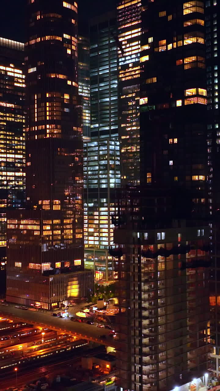 Car park and railway station at the base of beautiful high-rise buildings. Drone flying up along the modern skyscrapers. Vertical video