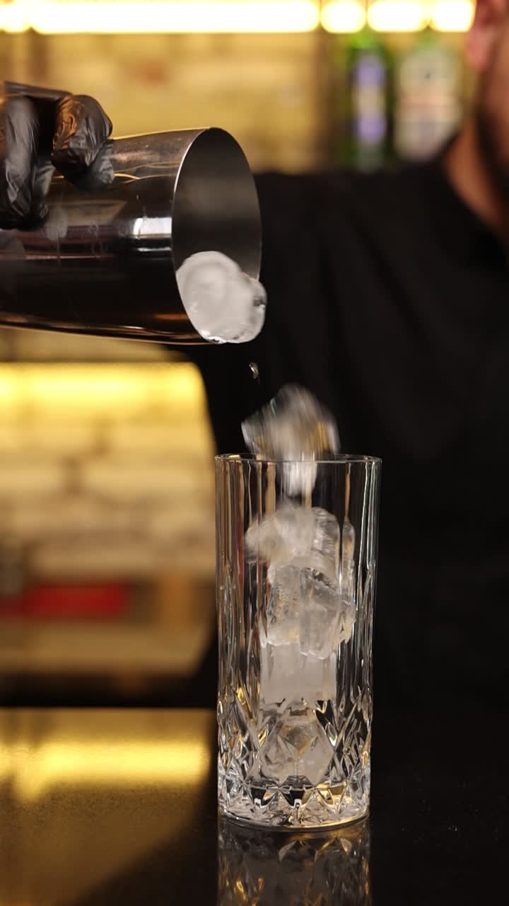 Barman che versa ghiaccio in un bicchiere da cocktail