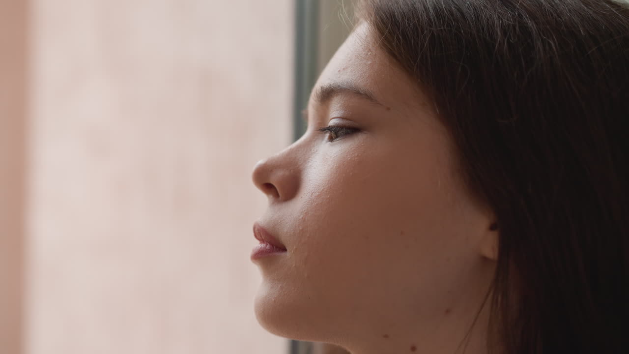 mujer mira por la ventana tristemente desde el interior. mujer atractiva se ocupa de problemas psicológicos sola en casa. mujer frustrada piensa demasiado la situación