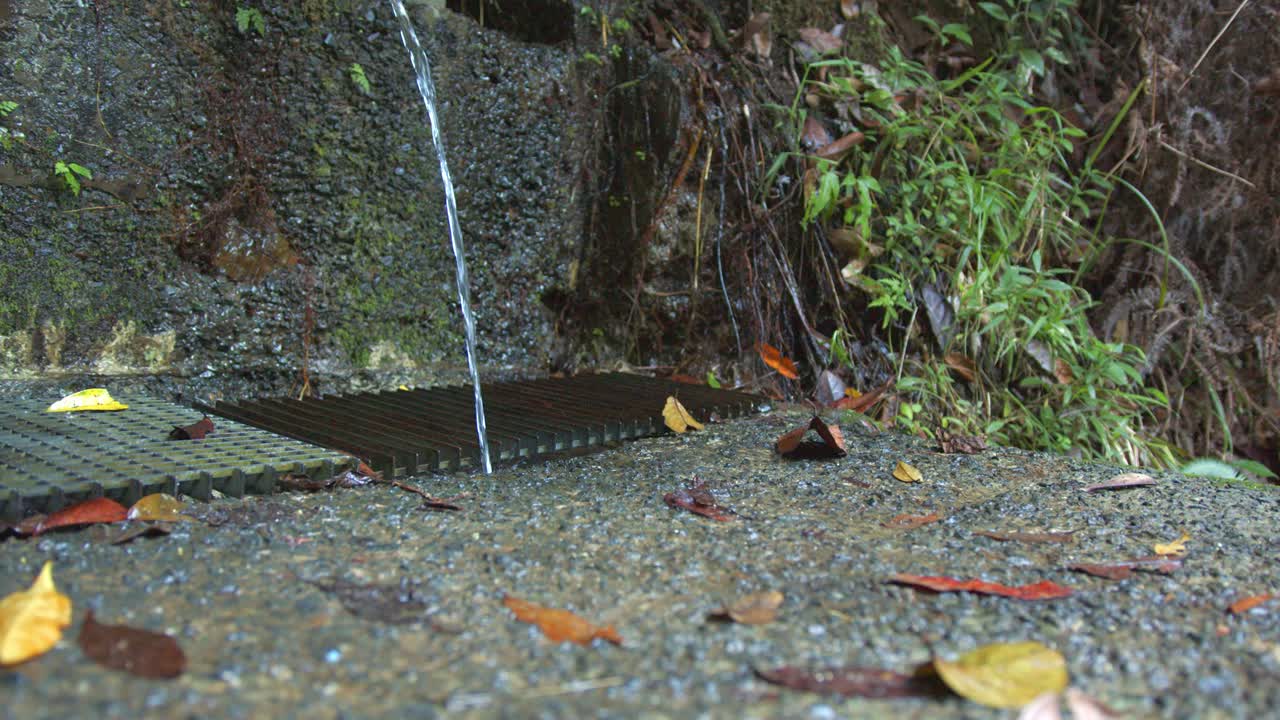 Crystal clear water flowing down a drain on rocky ground in nature