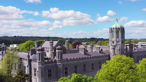 aerial view showcasing the quadrangle building at nuig framed by lush green trees on a sunny day