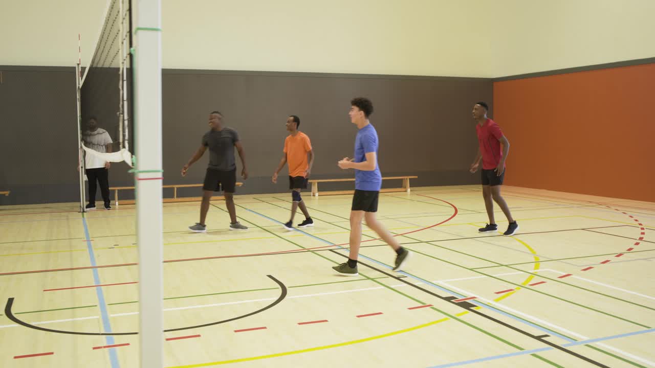 Diverse male players serving, spiking and digging after serve, competing for point at gym net