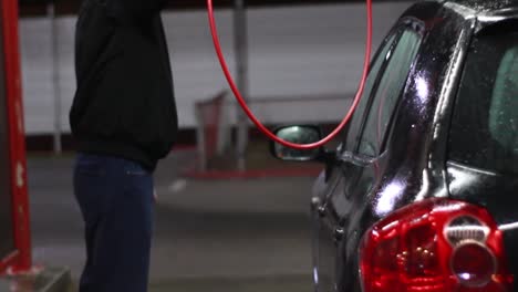 Man-on-manual-car-wash-at-night,-back-of-the-car