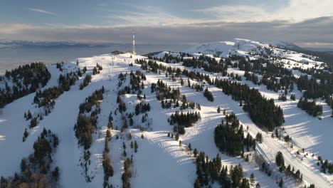 Beeindruckende-Drohnenaufnahme-Eines-Schneebedeckten-Und-Sonnigen-Berges-In-Europa