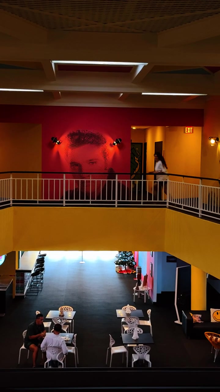 San Juan, Puerto Rico, 4 de agosto de 2025: Interior colorido de cafetería con arte mural. Interior moderno de cafetería con paredes amarillas brillantes, un mural artístico de retrato y gente sentada en las mesas, creando un ambiente urbano creativo.