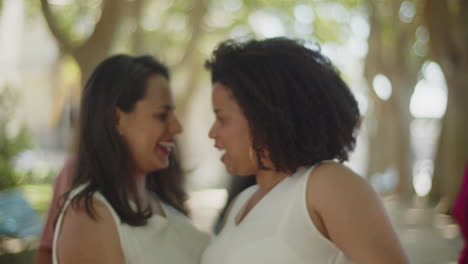 novias felices bailando con invitados en el parque de verano después de la ceremonia de boda