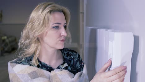 mujer en casa fría ajustando calentador eléctrico