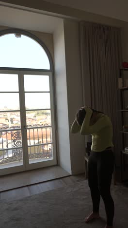 donna che si allunga a casa con vista sulla città