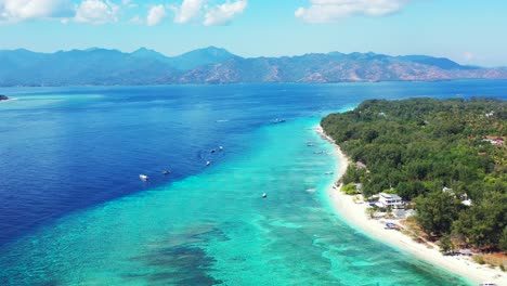 Beautiful-tropical-island-with-boats-on-the-surface-of-vibrant-turquoise-waters