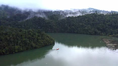 Sailboat-in-calm-Central-America-waters-with-tropical-forest-and-mist-in-background,-aerial