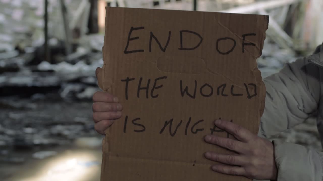 Hands holding sign warning of the end of world in rubble background