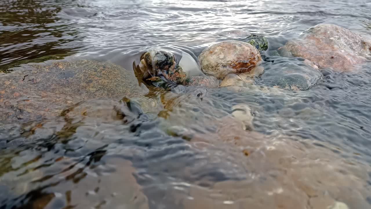 Crystal clear water of stream passing over stone dam. Close up