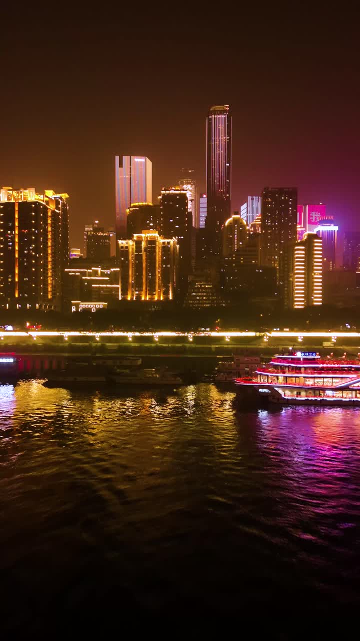 A river cruise ship illuminated with vibrant lights, cruising along the Yangtze River in Chongqing, China. A stunning night scene with reflections and modern city lights along the waterfront.