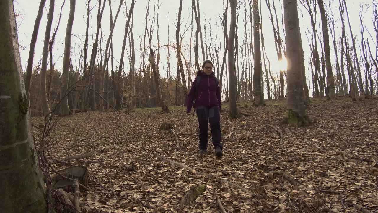 Young woman hiking alone in the woods walking downhill