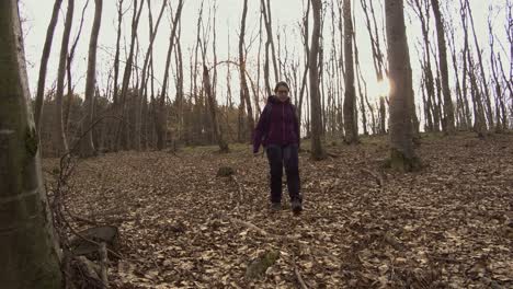 mujer joven caminando sola en el bosque caminando cuesta abajo