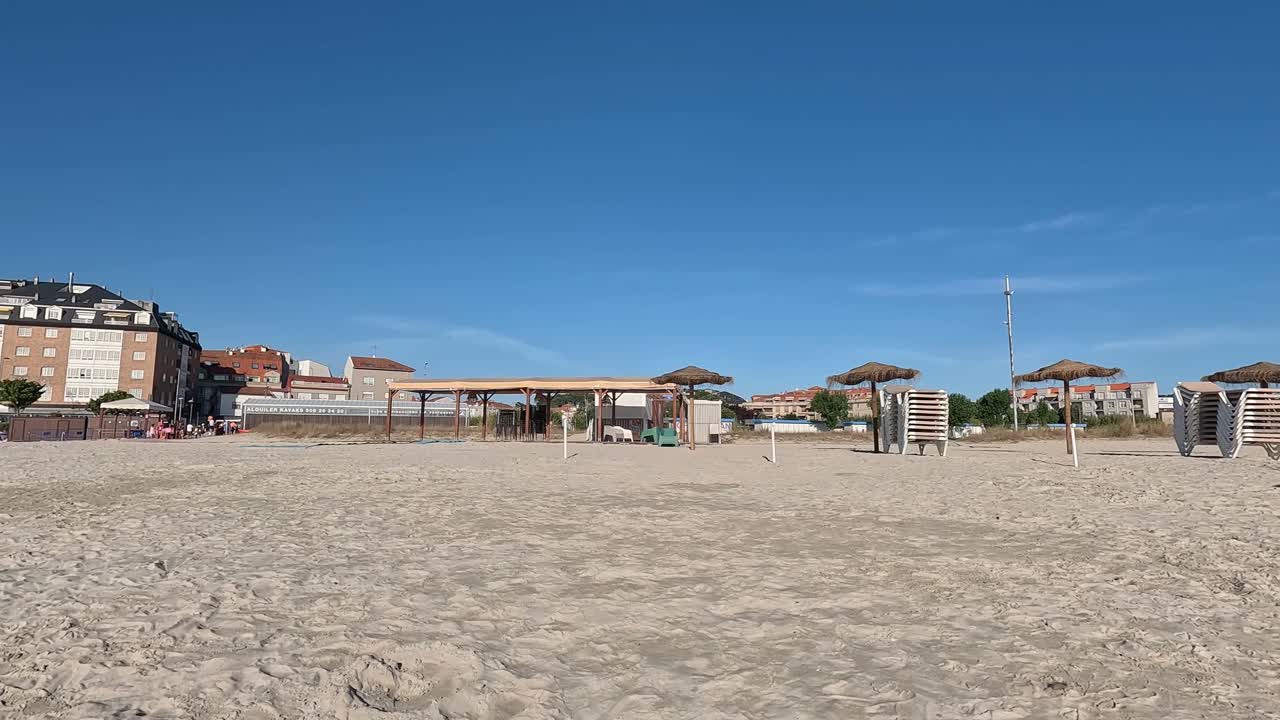 edificios frente a la playa, la gente viene por la mañana a tomar el sol y tomar un baño, sombrillas y sillas de sol se recogen y vacías, navegación descriptiva