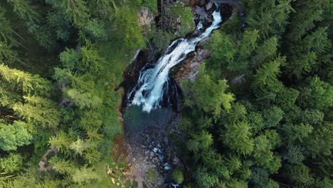 Bird's-eye-view-of-impressive-Gollinger-Waterfall-surrounded-by-trees,-aerial