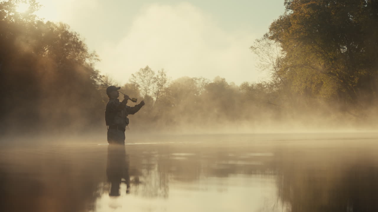 Fisherman in a misty morning river