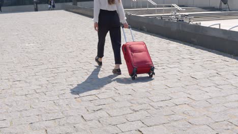 Fashionable-woman-traveling-with-red-luggage,-back-view