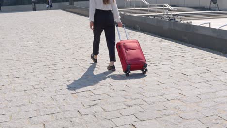 mujer de moda viajando con equipaje rojo, vista trasera