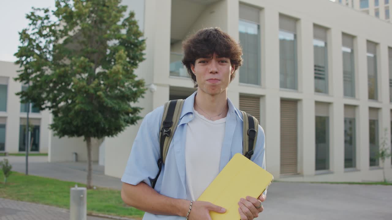Teenage student with backpack and tablet outside school building