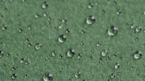 micro video of close up of water drops with copy space on green background