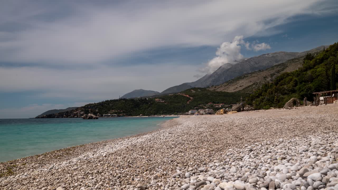 Albanian beach with rocky shore under dynamic sky, serene timelapse view