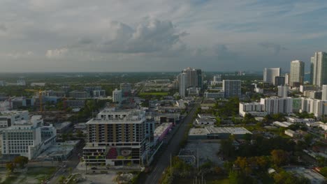 forwards fly above contemporary urban borough in golden hour. buildings lit by bright low sun. miami, usa