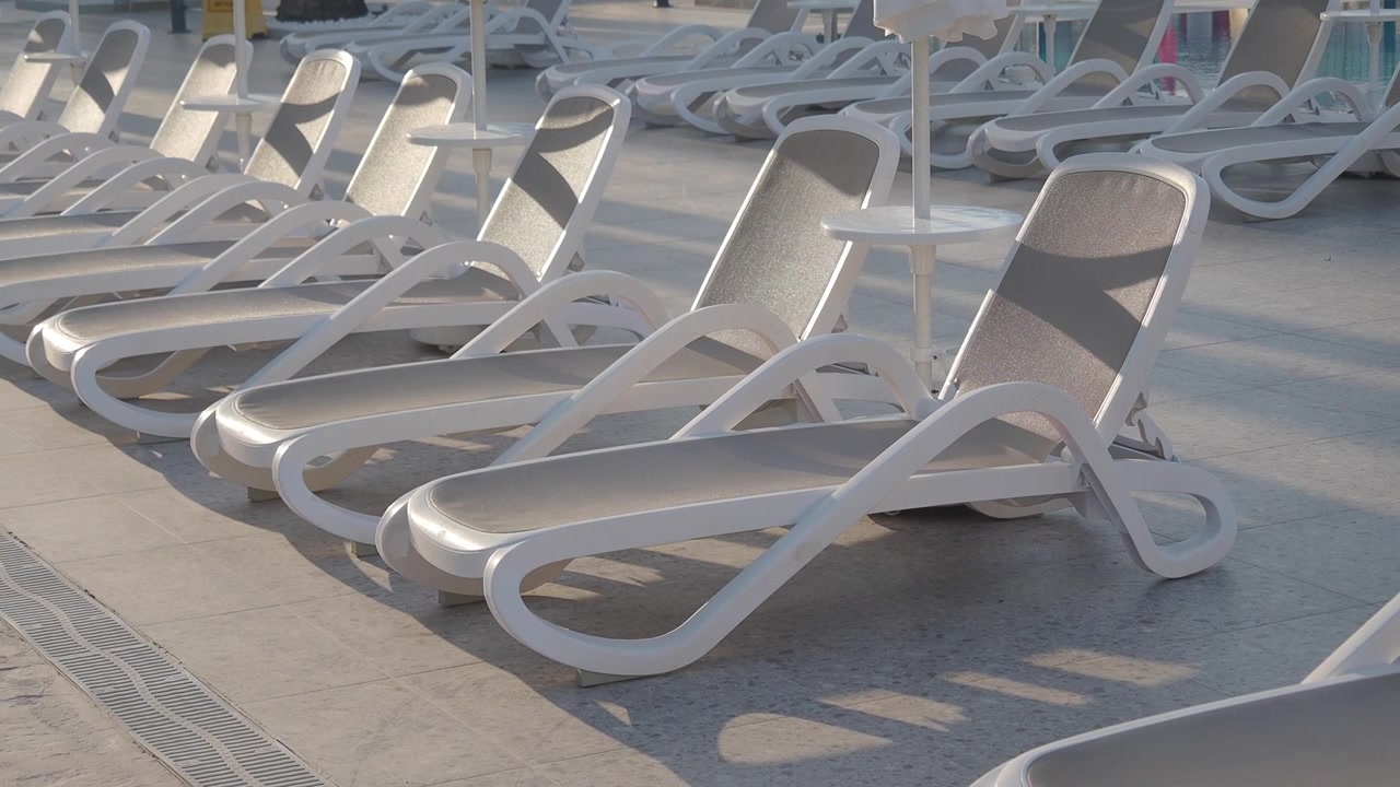 Rows of Empty Sun Loungers by a Resort Swimming Pool
