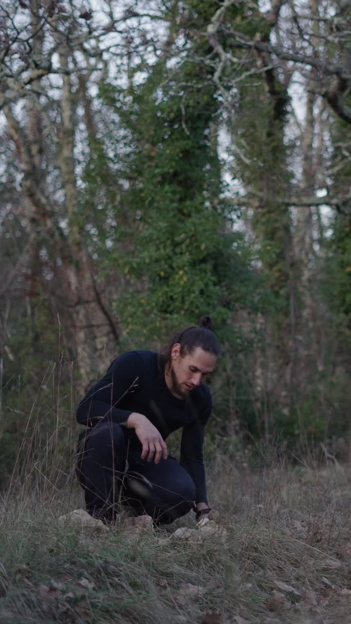 Man squatting in the forest