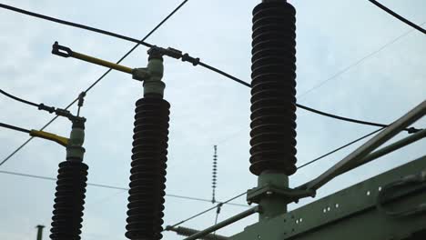 Primer-Plano-De-Aisladores-Eléctricos-Y-Cables-Contra-Un-Cielo-Nublado,-Concepto-De-Energía-Industrial