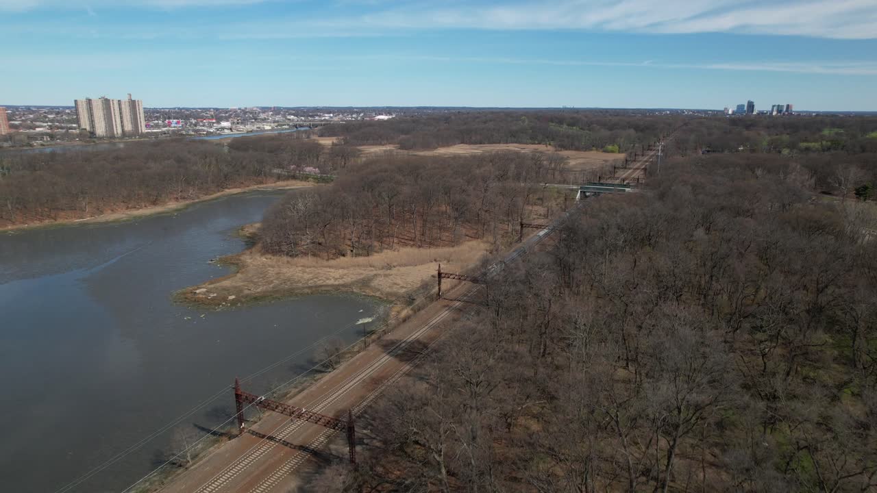 An aerial view of a train approaching, traveling towards the Pelham Bay Railroad Bridge in The Bronx, New York on a sunny morning