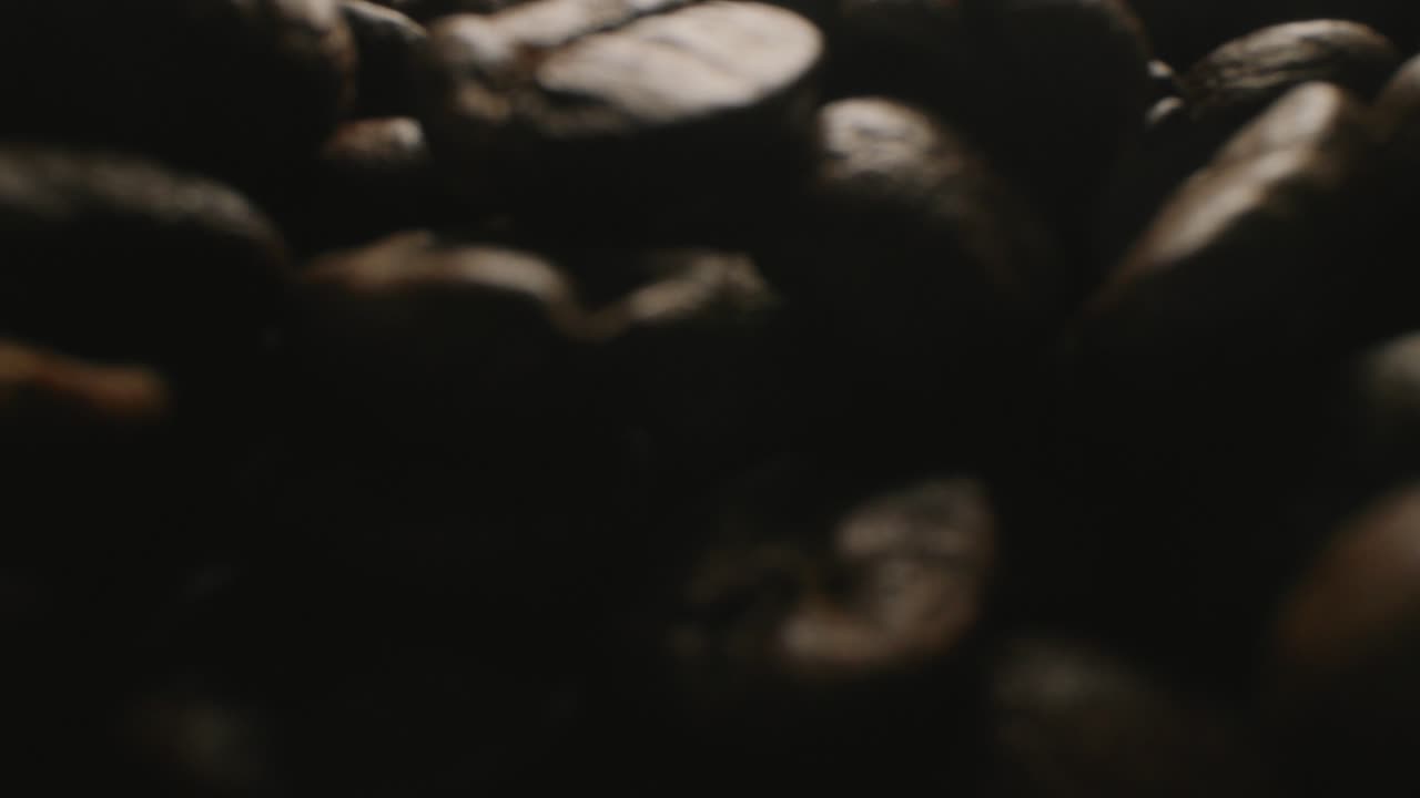 Close up slider shot that is emerging from a pile of roasted coffee beans.