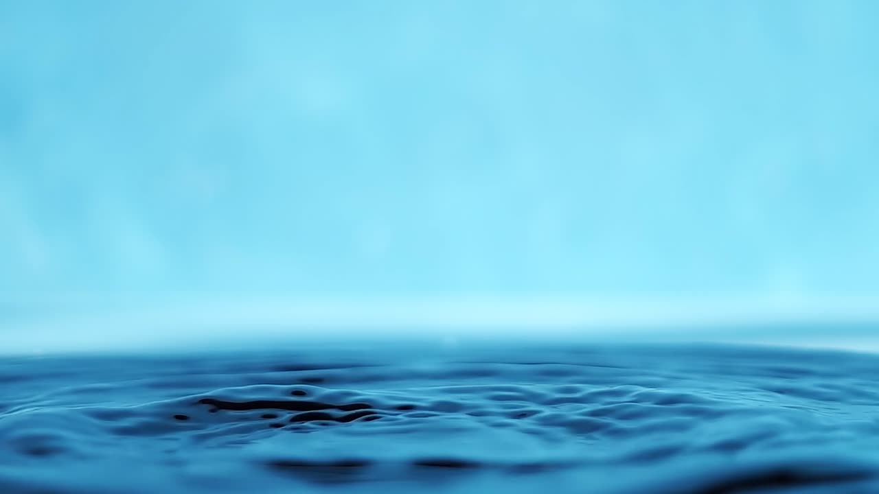 파란색 배경에 떨어지는 물방울과 함께 물 표면의 느린 모션 4k 비디오.