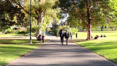 dos hombres caminando en un parque soleado