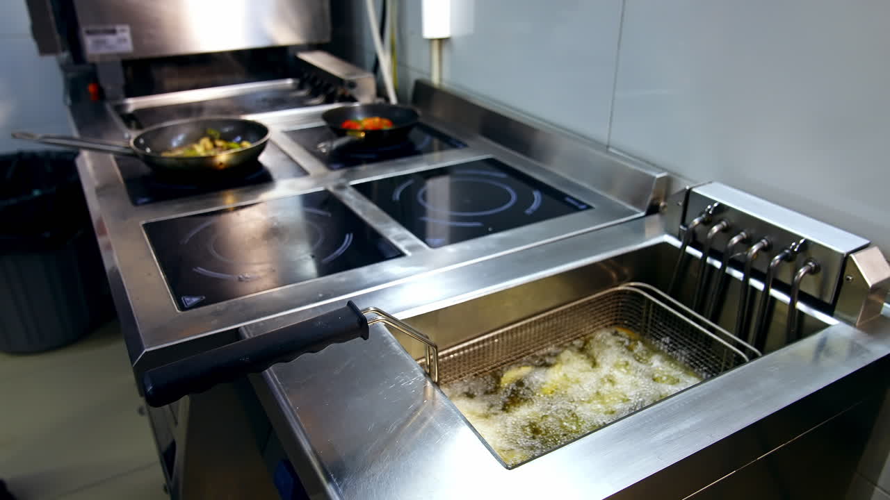 Cooking meals in the restaurant kitchen. French fries in a deep fryer on the background of frying pans on a stove. Crispy potatoes in a deep fryer.