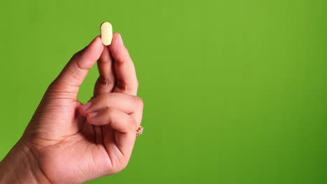 hand holding a light yellow pill