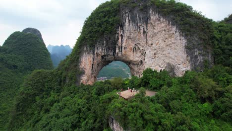 Tourists-admiring-Moon-Hill-or-Yueliang-Shan-with-city-view-behind,-Yangshuo,-China