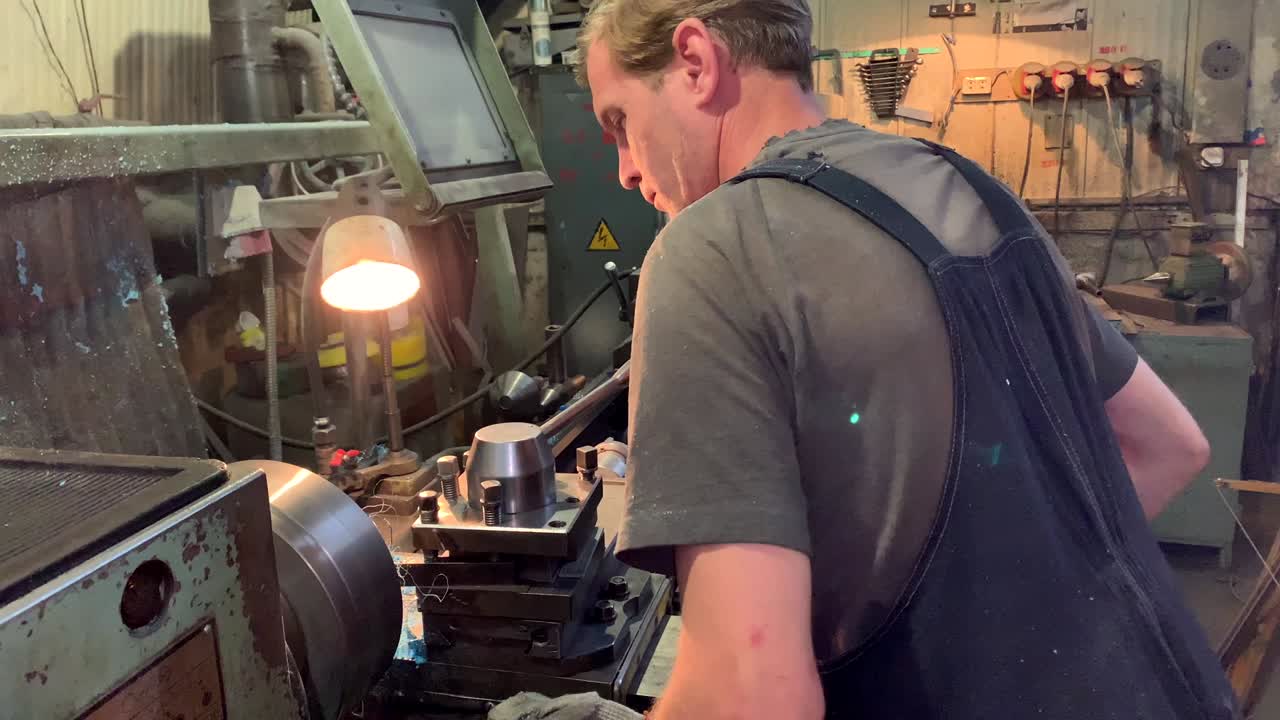 Torneiro atrás de uma máquina de torneamento e fresagem