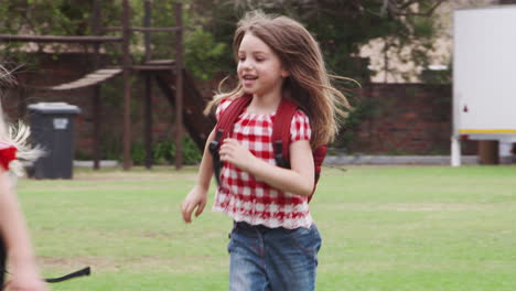 excited elementary school pupils wearing uniform running across field at break time