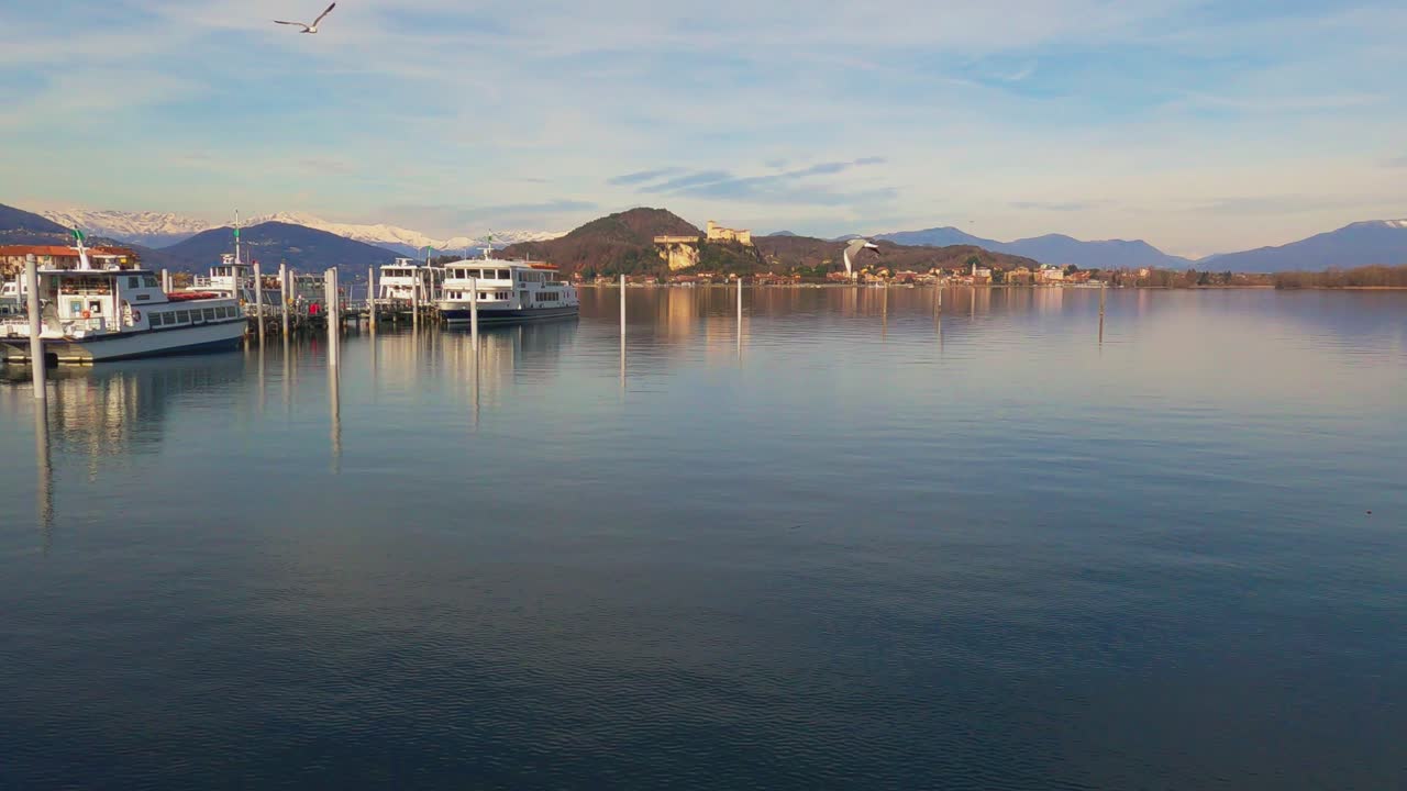 barcos amarrados en el lago maggiore y el castillo de angrya en el fondo, italia