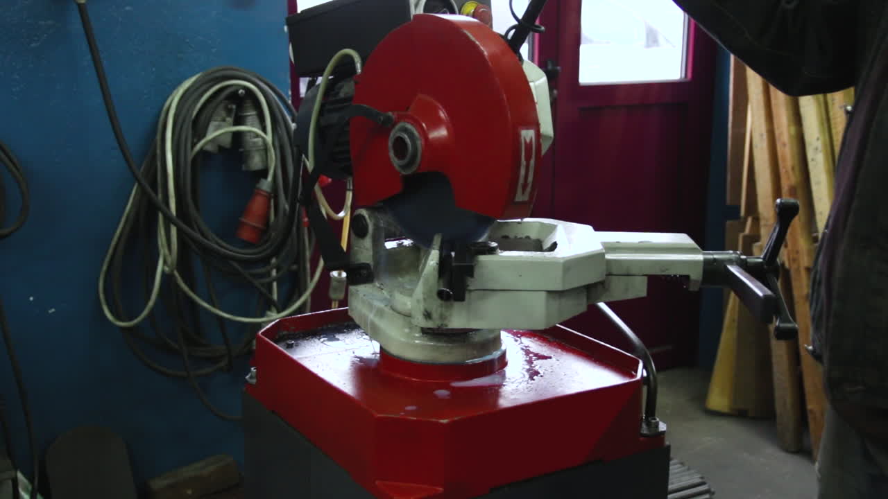 The man works in the workshop, cuts through metal parts with a metal cutter