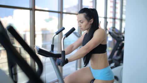 active beautiful girl working hard on a stationary bike indoors active beautiful girl working hard on a stationary bike indoors caucasian sportswoman looking cheerful while burning calories in gym high quality footage