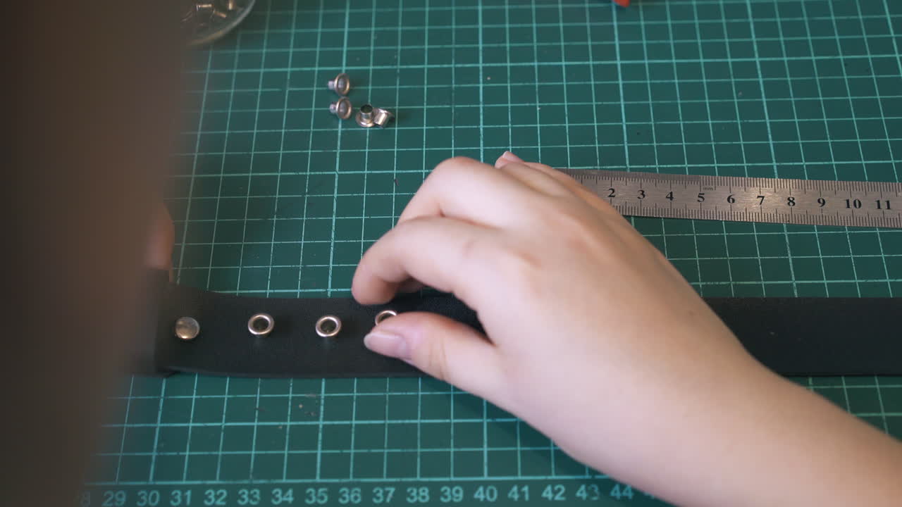 숙련 된 맞춤사 는 검은 가죽 벨트 에 금속 액세서리 를 착용 한다