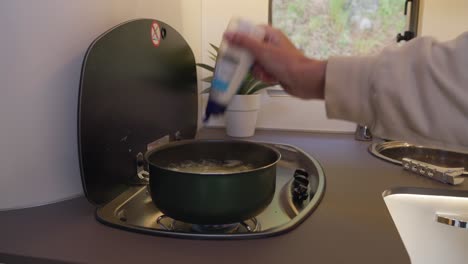 adding salt to boiling pot for making mashed potatoes in camper kitchen