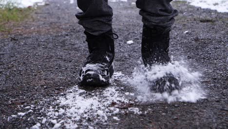 primer plano de la persona agitar las botas de nieve al aire libre durante el día de invierno con nieve