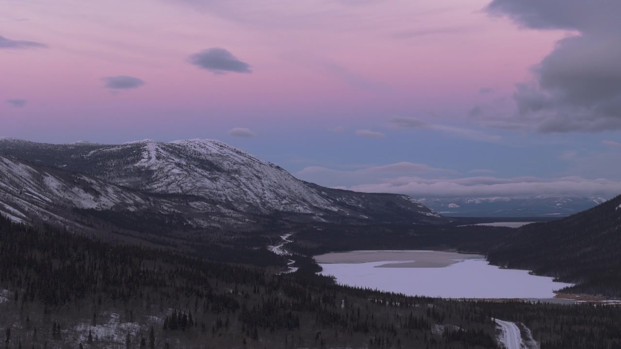 Pink Skies Over The Snowy Mountain And Bennet Lake During Winter In Yukon, Canada. - aerial shot