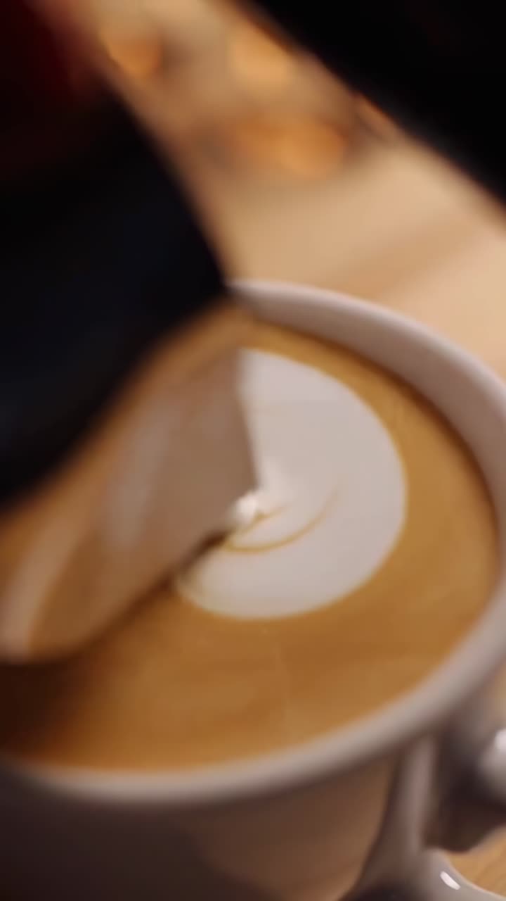 Video in primo piano di caffè espresso che si versa in una tazza, catturando texture ricche da un'angolazione bassa.